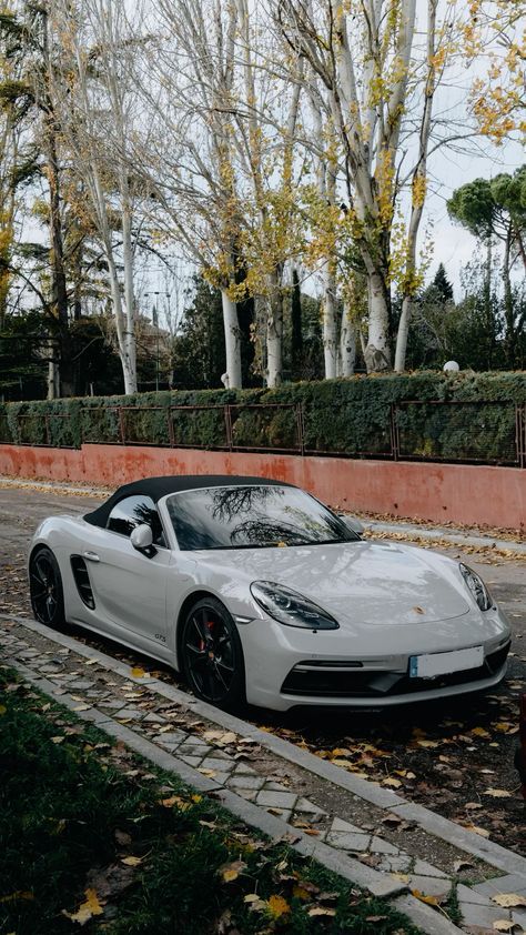 a white sports car is parked on the side of the road in front of some trees