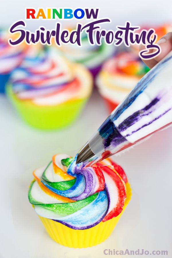 a cupcake with rainbow frosting being piped into the icing to decorate it