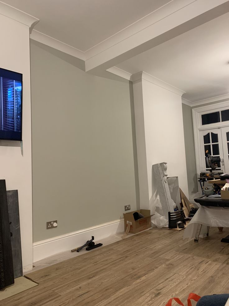 a living room with hard wood flooring and a flat screen tv mounted on the wall