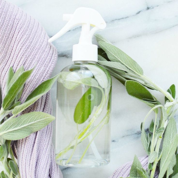 a bottle of hand sanitizer with green leaves and lavender on the table next to it