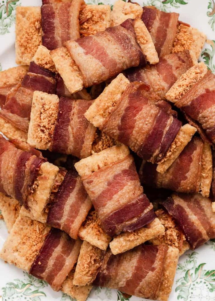 bacon wrapped in crumbs on a white and green platter with floral designs