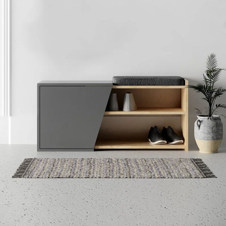 a grey cabinet sitting on top of a rug next to a vase and potted plant