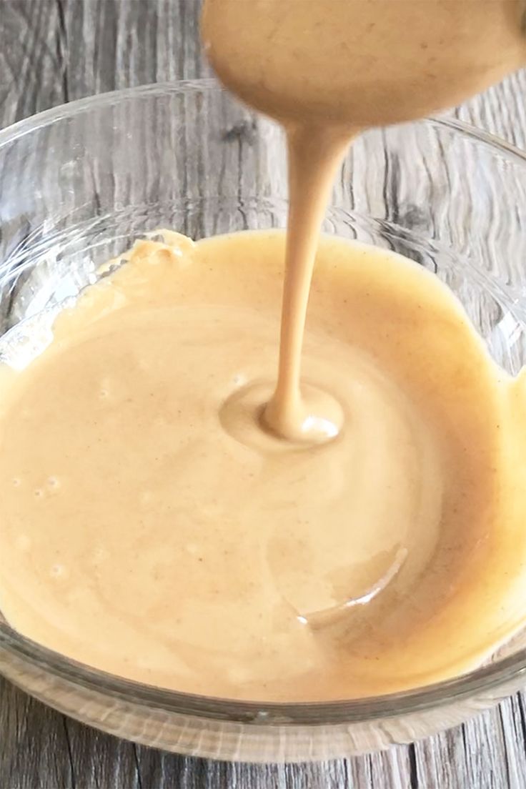 a glass bowl filled with peanut butter on top of a wooden table