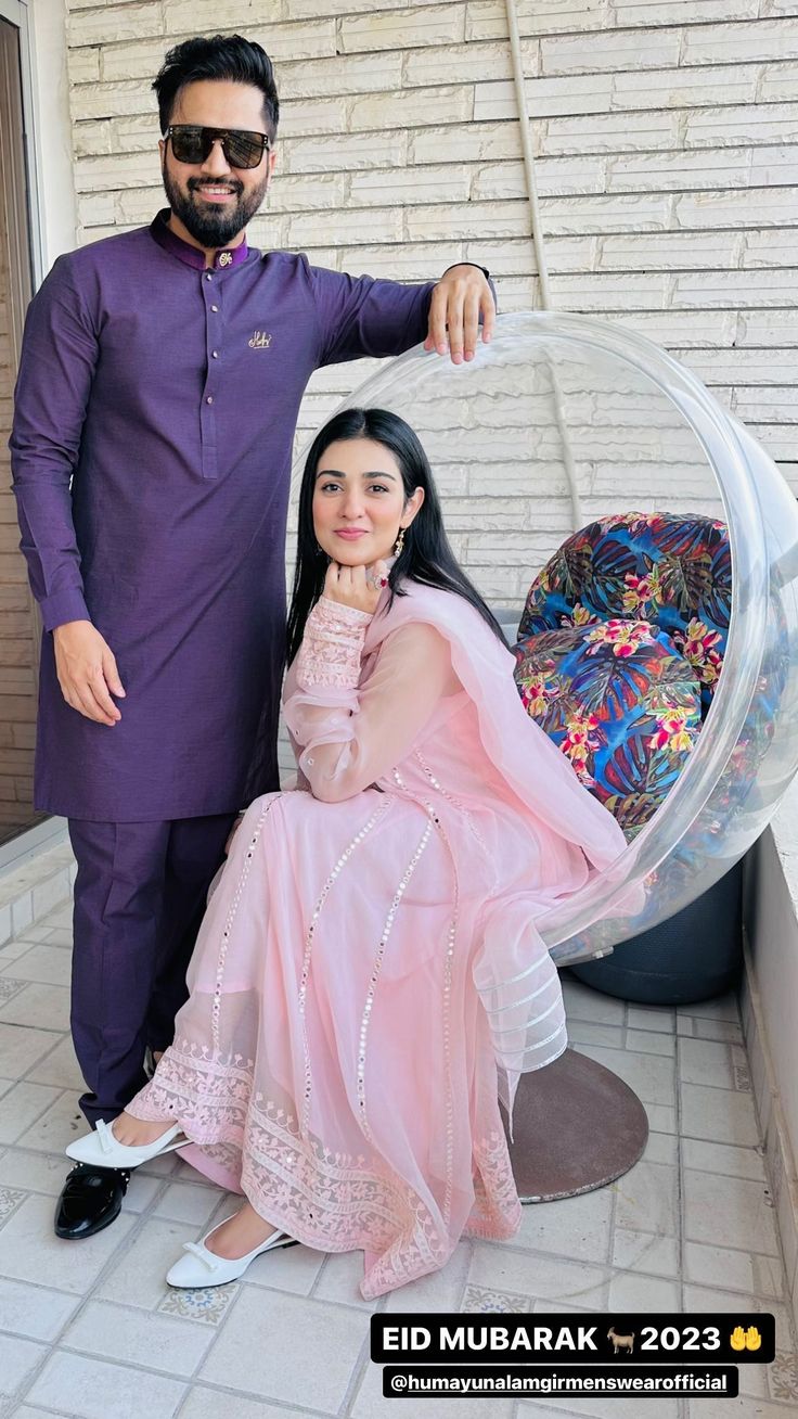 a man standing next to a woman in a pink dress on top of a chair