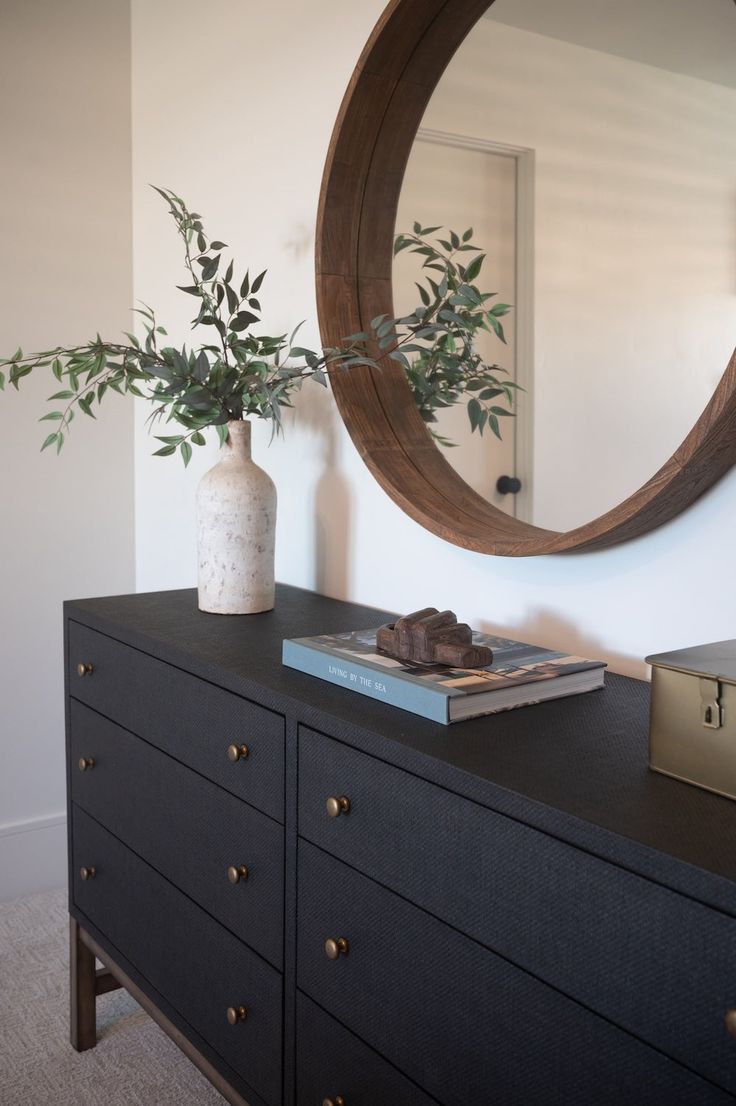 there is a vase with some plants on top of the dresser