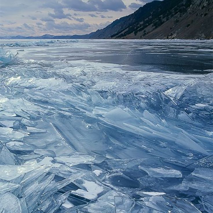 an ice floet with mountains in the background and water flowing down it's sides