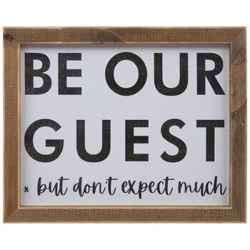 a wooden framed sign that says be our guest but don't expect much on it