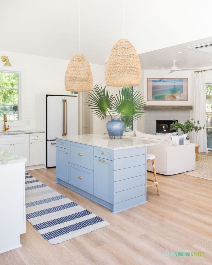 a kitchen with blue cabinets and white counter tops next to a living room filled with furniture