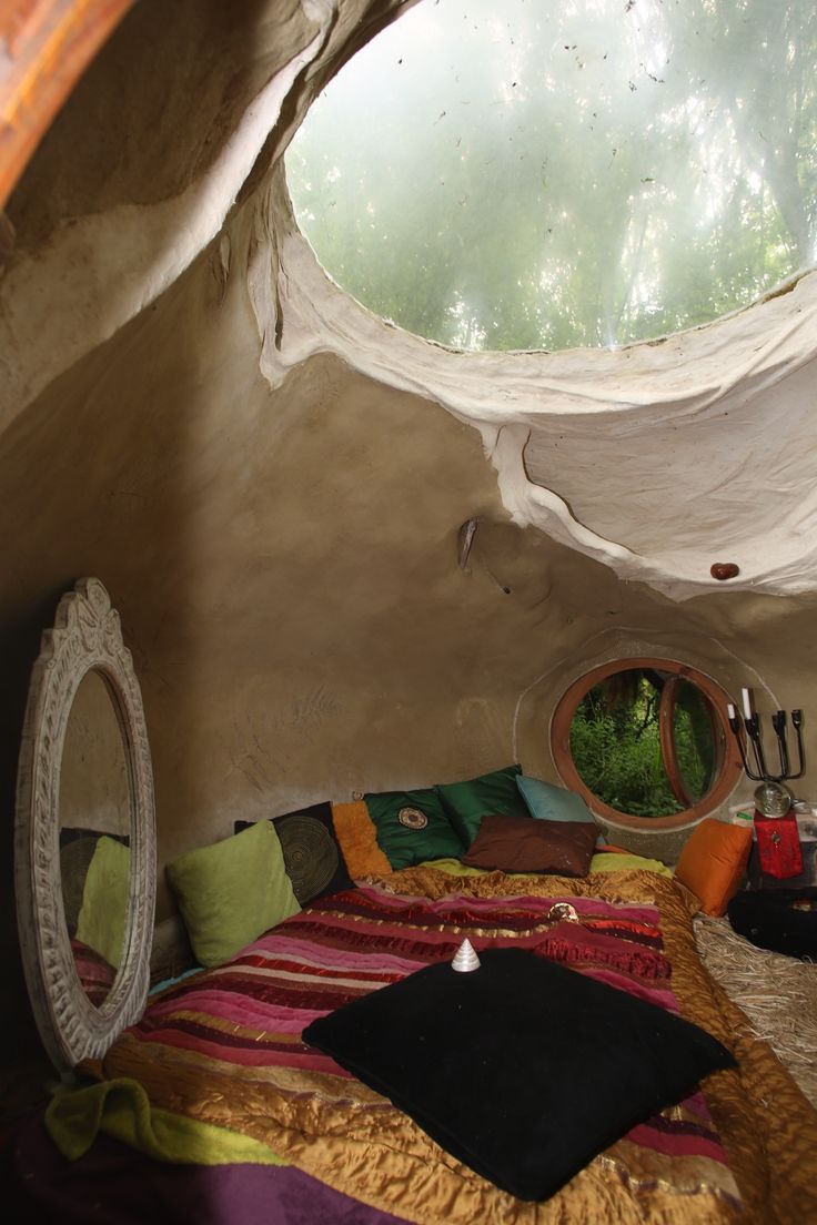 a bed sitting inside of a bedroom next to a round mirror on top of a wall