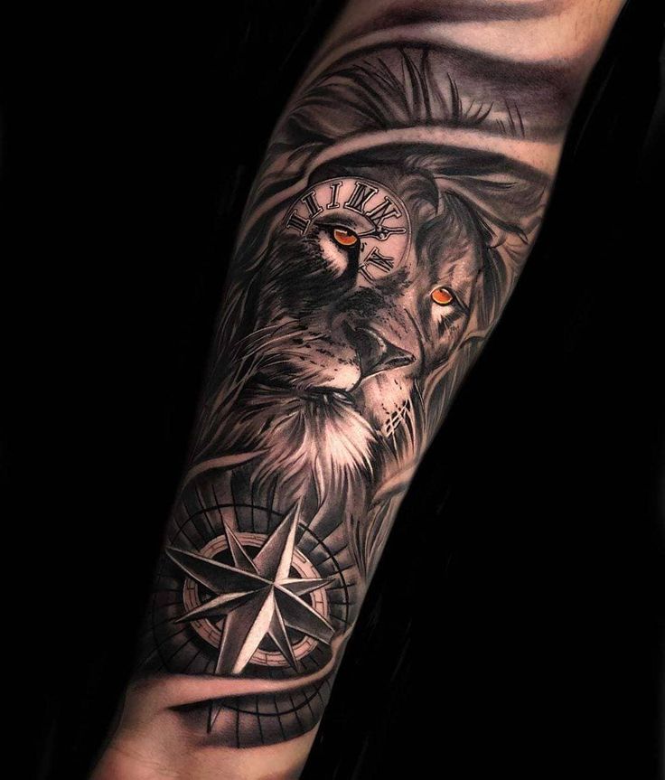 a man's arm with a lion and compass tattoo on it