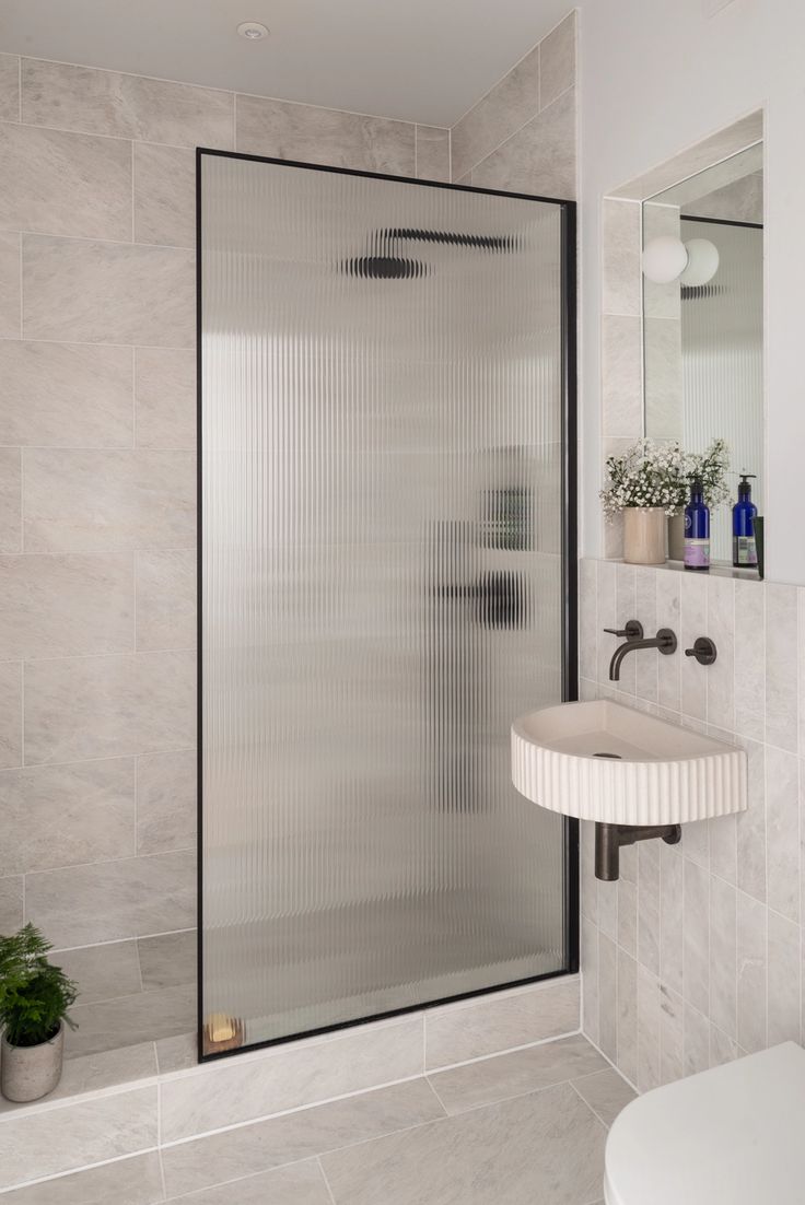 a bathroom with a sink, toilet and shower stall in the wall next to it