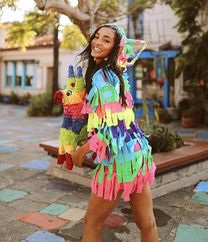 a woman in a colorful dress is holding a stuffed animal and smiling at the camera