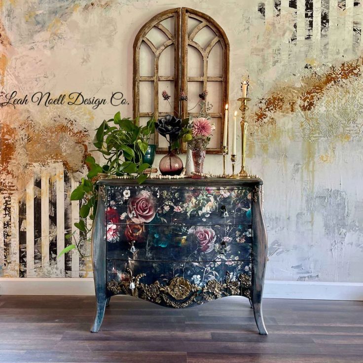 an old dresser with flowers on it in front of a painted wall and wooden floor