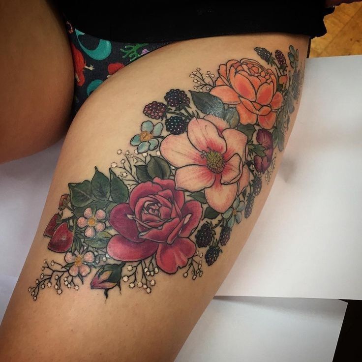 a woman's thigh with flowers and leaves on it