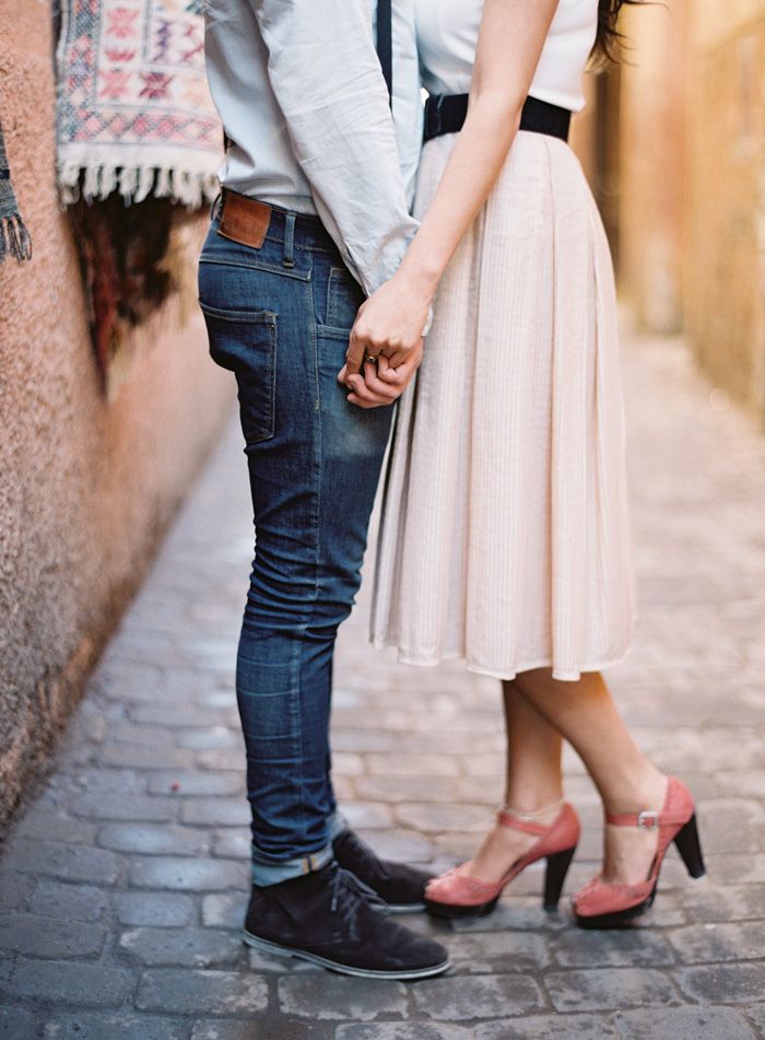 a man and woman standing next to each other on a brick road holding hands with one another