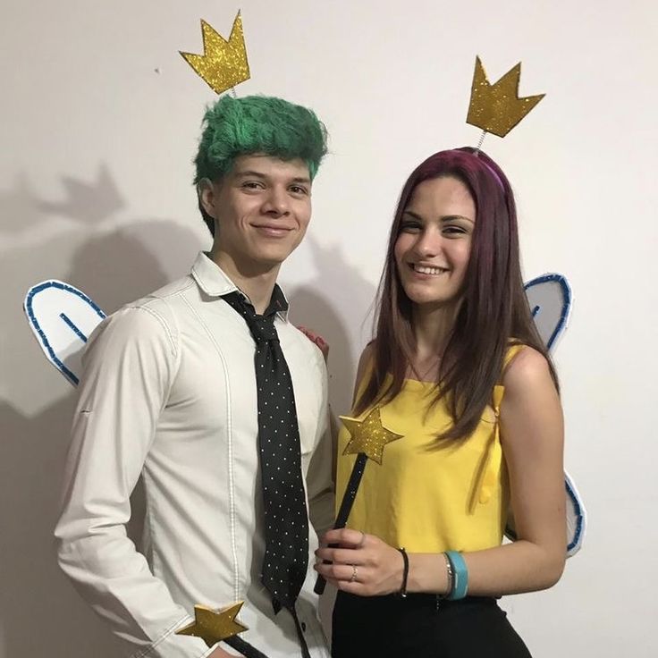 a man and woman posing for a photo in front of a wall with gold stars on it