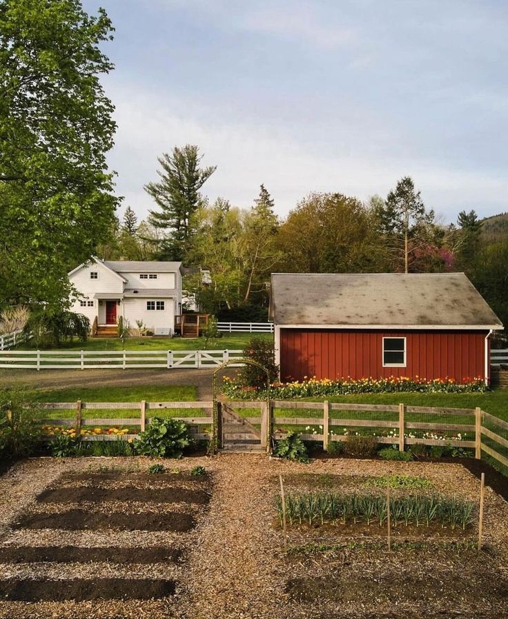 a red barn sits in the middle of a garden