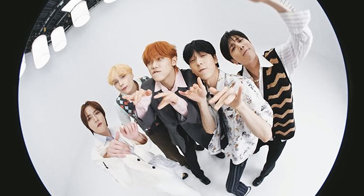 group of young men standing in front of a white background with their hands up to the side