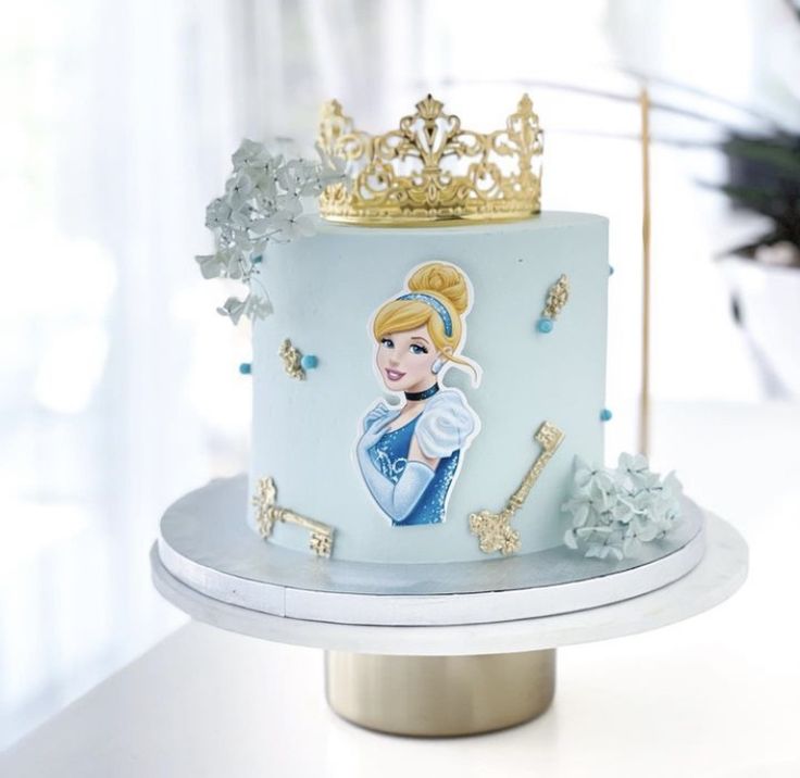 there is a blue cake with a princess on it and gold trim around the edges