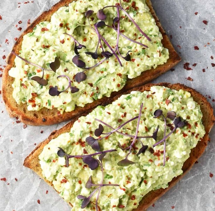 two pieces of bread topped with guacamole and purple sprinkles