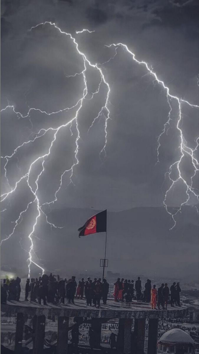 a group of people standing on top of a roof under lightning strikes in the sky