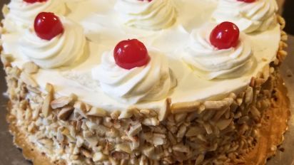 a cake with white frosting and cherries on top