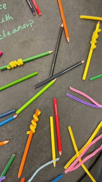 there are many different colored pencils on the table with words written in chalk next to them