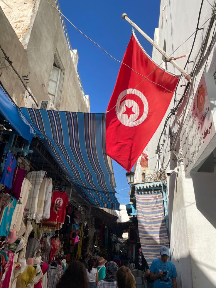 a red and white flag hanging from the side of a building next to other buildings