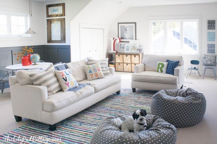 a living room filled with white furniture and lots of pillows on top of the floor