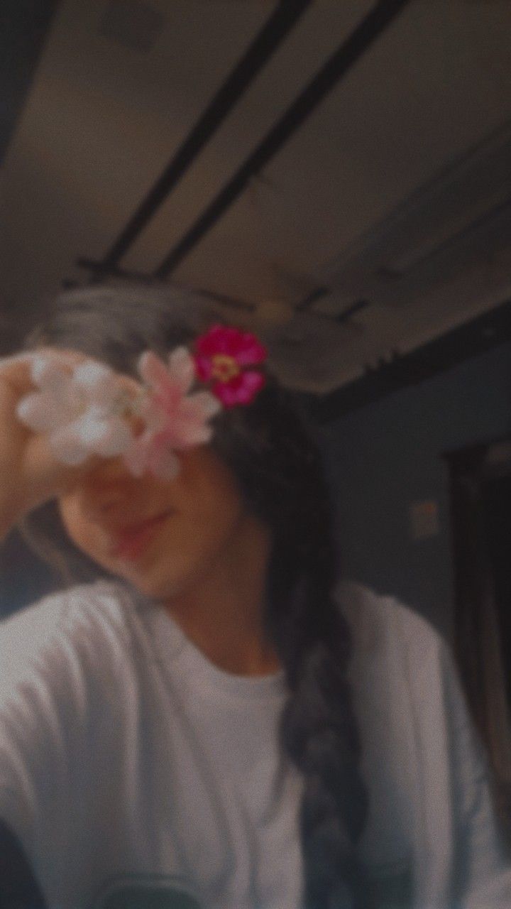 a girl with long braids and a flower in her hair looking through the window