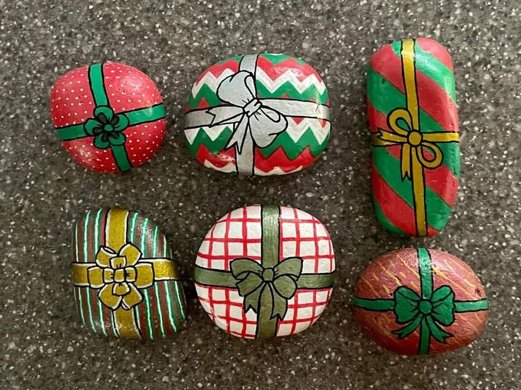 painted rocks with bows and presents on them sitting on the ground next to each other