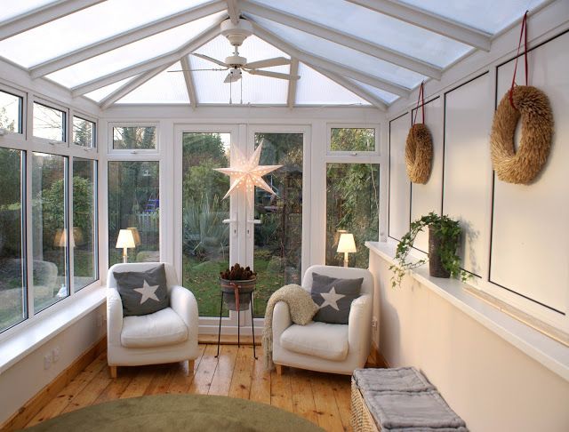 a sun room with two white chairs and a green rug