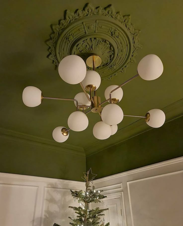 a christmas tree is in the middle of a room with green walls and ceiling paint