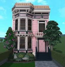 a pink and black house sitting on top of a lush green field