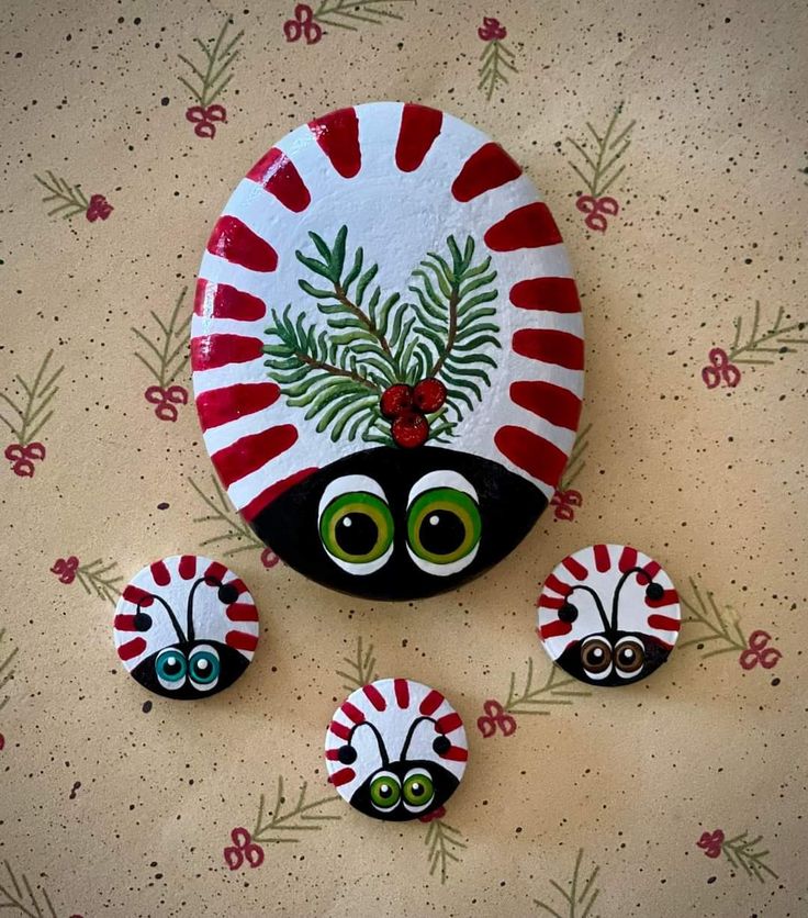 three painted rocks sitting on top of a table next to each other with eyes and leaves