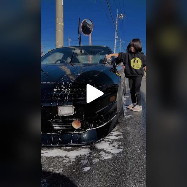 a person washing a black car in the street