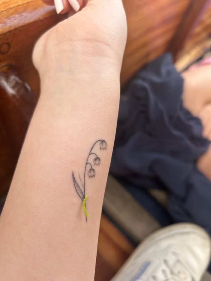 a woman's arm with a small flower tattoo on the left side of her arm