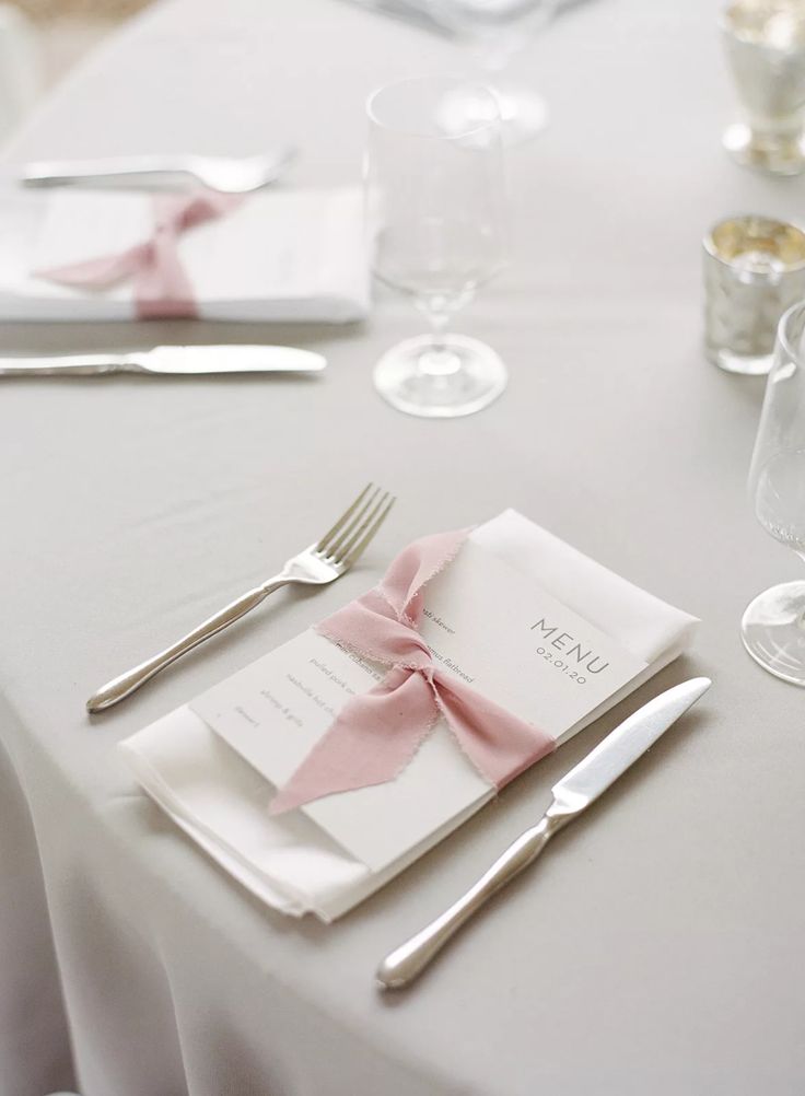 the table is set with silverware and napkins, along with pink bow ties