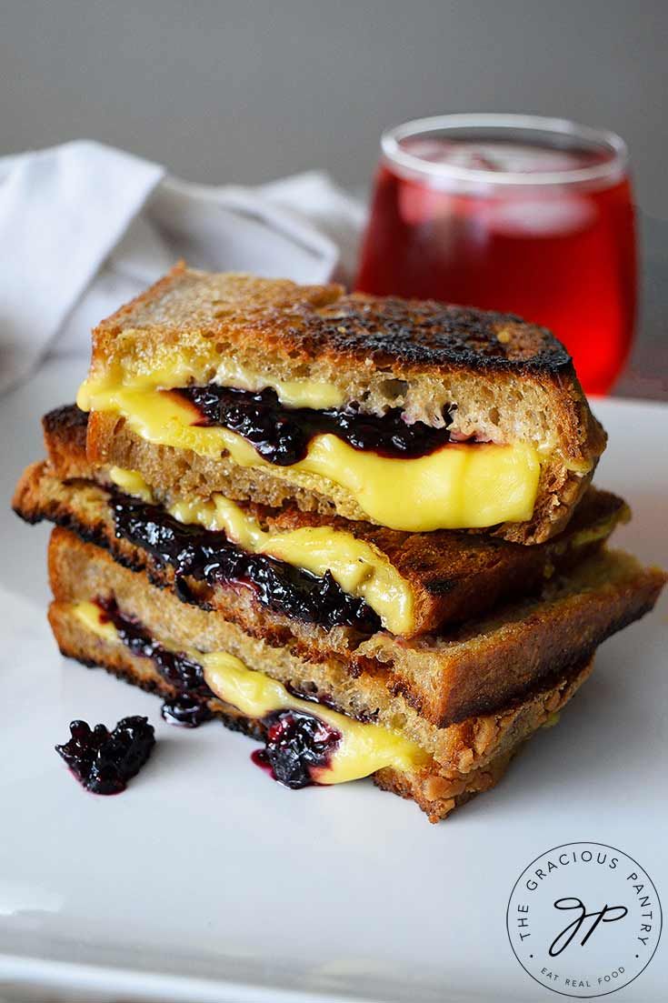 two grilled cheese sandwiches stacked on top of each other with blueberry sauce in the middle