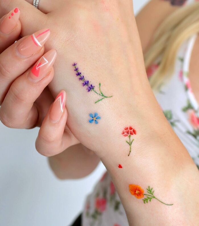 a woman's arm with flowers on it and her hand holding the wrist tattoo