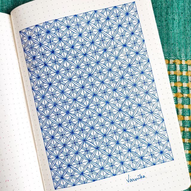 an open notebook with blue and white designs on the cover, sitting on a green cloth