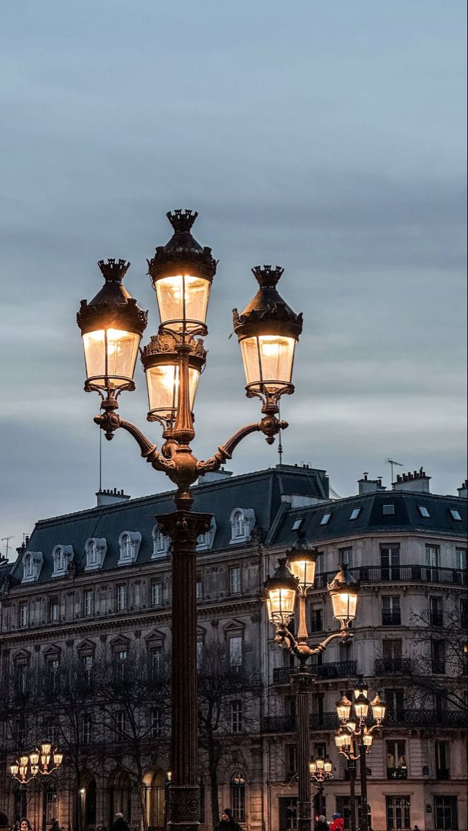 a street light in the middle of a city at night with people walking around it