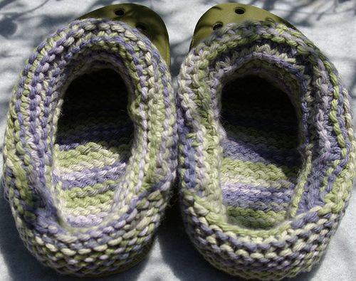 two crocheted slippers sitting on top of a blanket