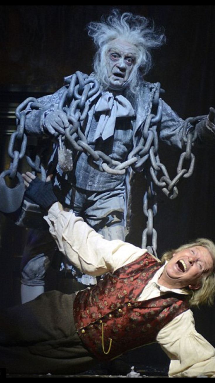 the actors are performing on stage with chains hanging from their arms and hands in the air