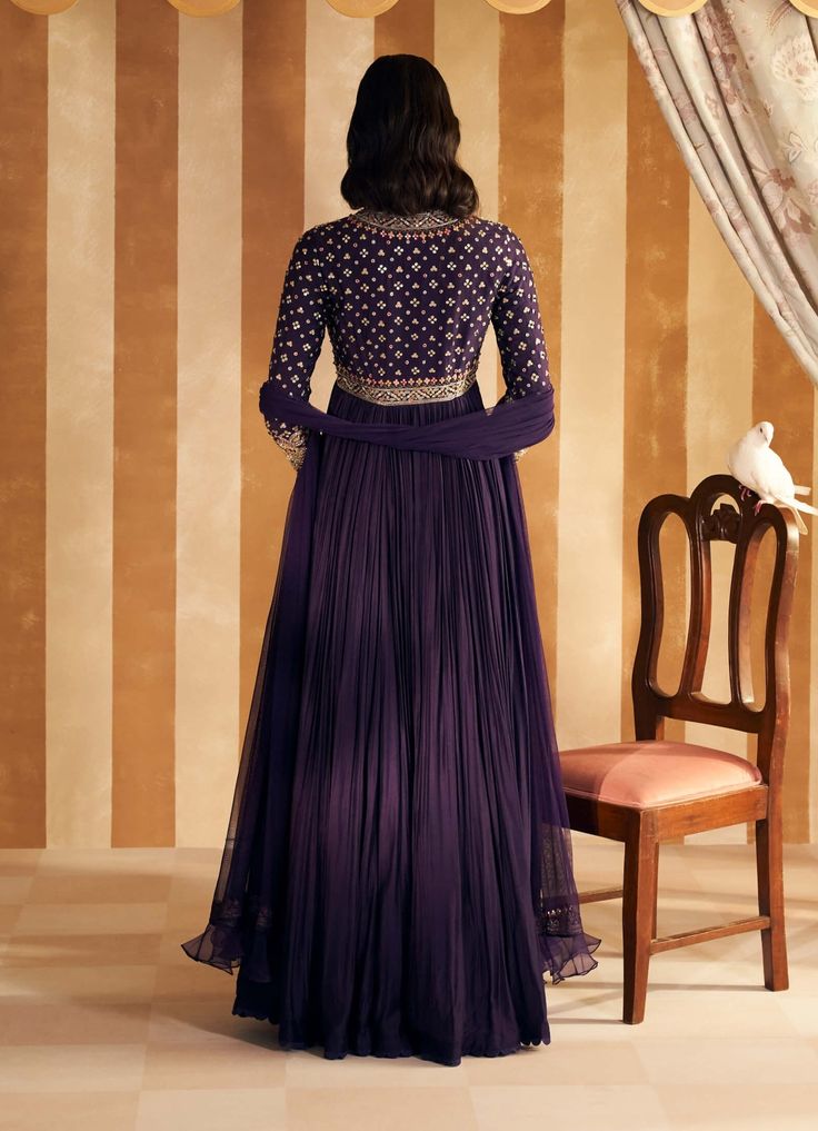 Embrace regal sophistication with this purple fine silk long anarkali. The sumptuous silk fabric is richly adorned with intricate embroidery, offering a luxurious sheen and graceful flow. Paired with a net embroidered dupatta, this ensemble exudes elegance and charm, making it perfect for any special occasion. Purple Churidar With Intricate Embroidery, Embroidered Floor-length Purple Churidar, Embroidered Purple Floor-length Churidar, Purple Long Sleeve Sharara With Intricate Embroidery, Purple Floor-length Churidar With Resham Embroidery, Purple Resham Embroidery Floor-length Churidar, Embroidered Purple Churidar For Weddings, Purple Resham Embroidered Floor-length Churidar, Designer Purple Churidar With Intricate Embroidery