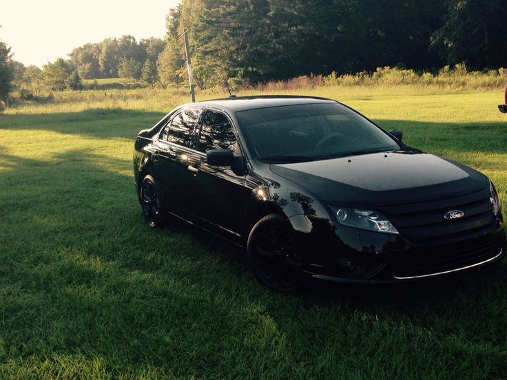 a black car parked on top of a lush green field