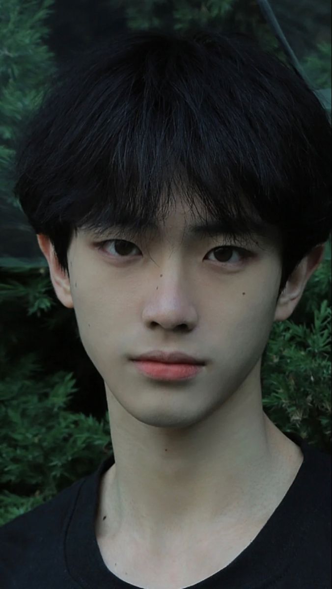 a young man with black hair and an umbrella over his head is staring at the camera