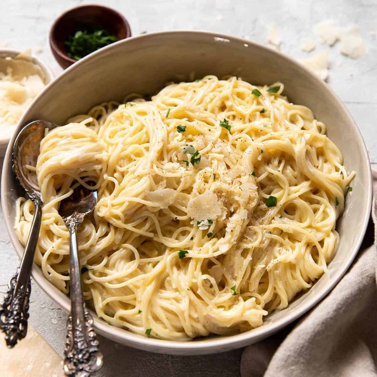 a bowl of pasta with chicken and parmesan cheese on the side, ready to be eaten