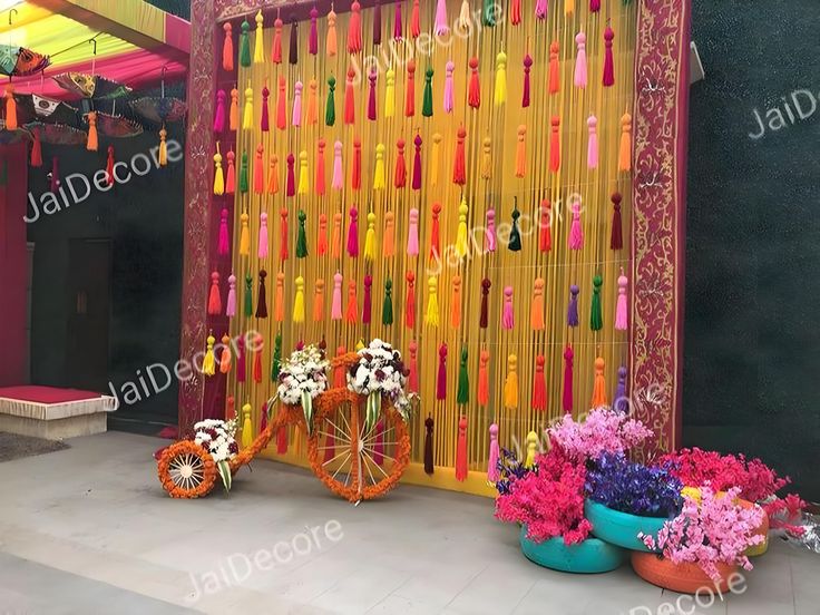 colorful decorations and flowers are displayed in front of a wall made out of colored sticks