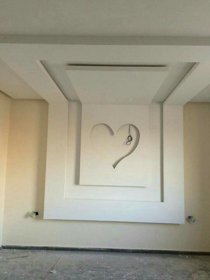 a clock in the middle of a room with a heart drawn on it's wall